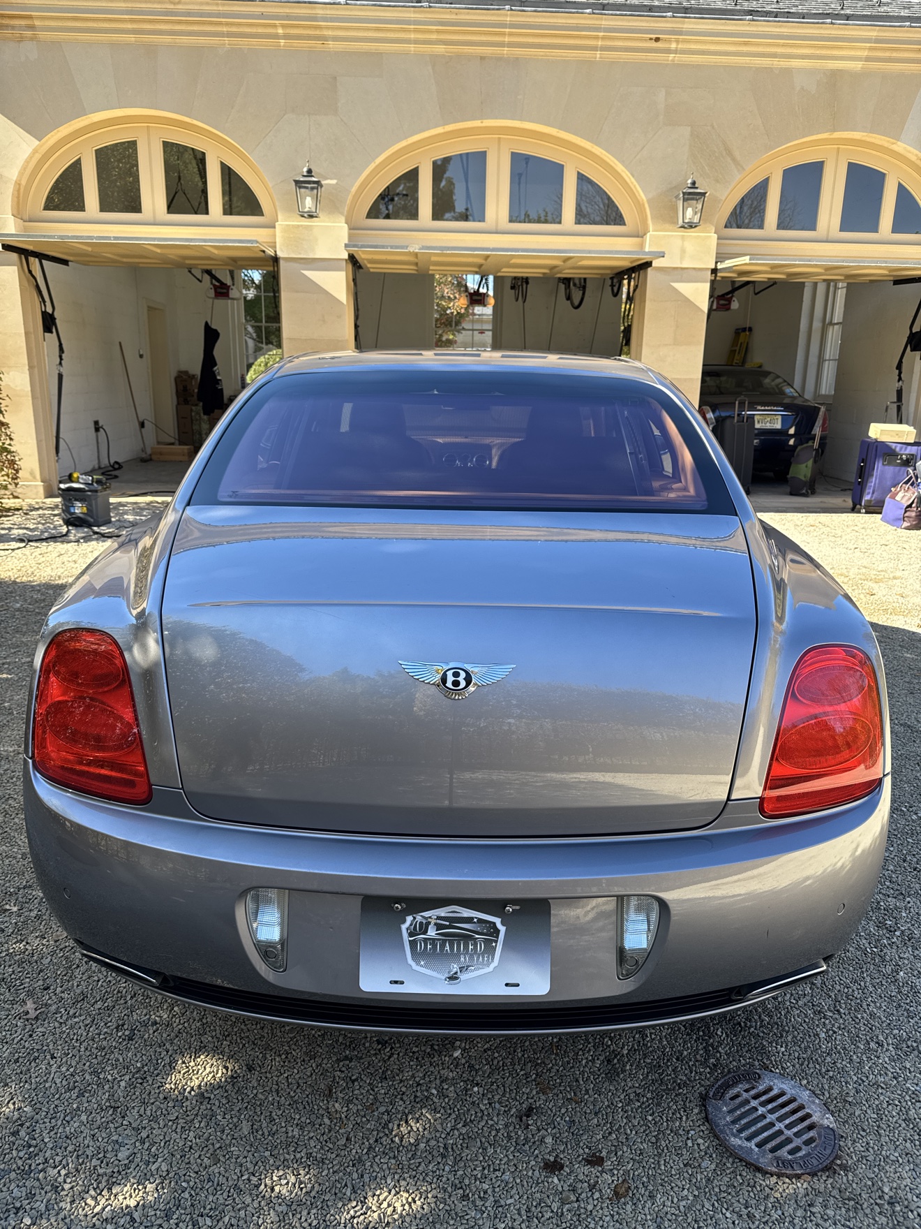 Rear view of a silver Bentley Continental with Detailed by Yael plate frame