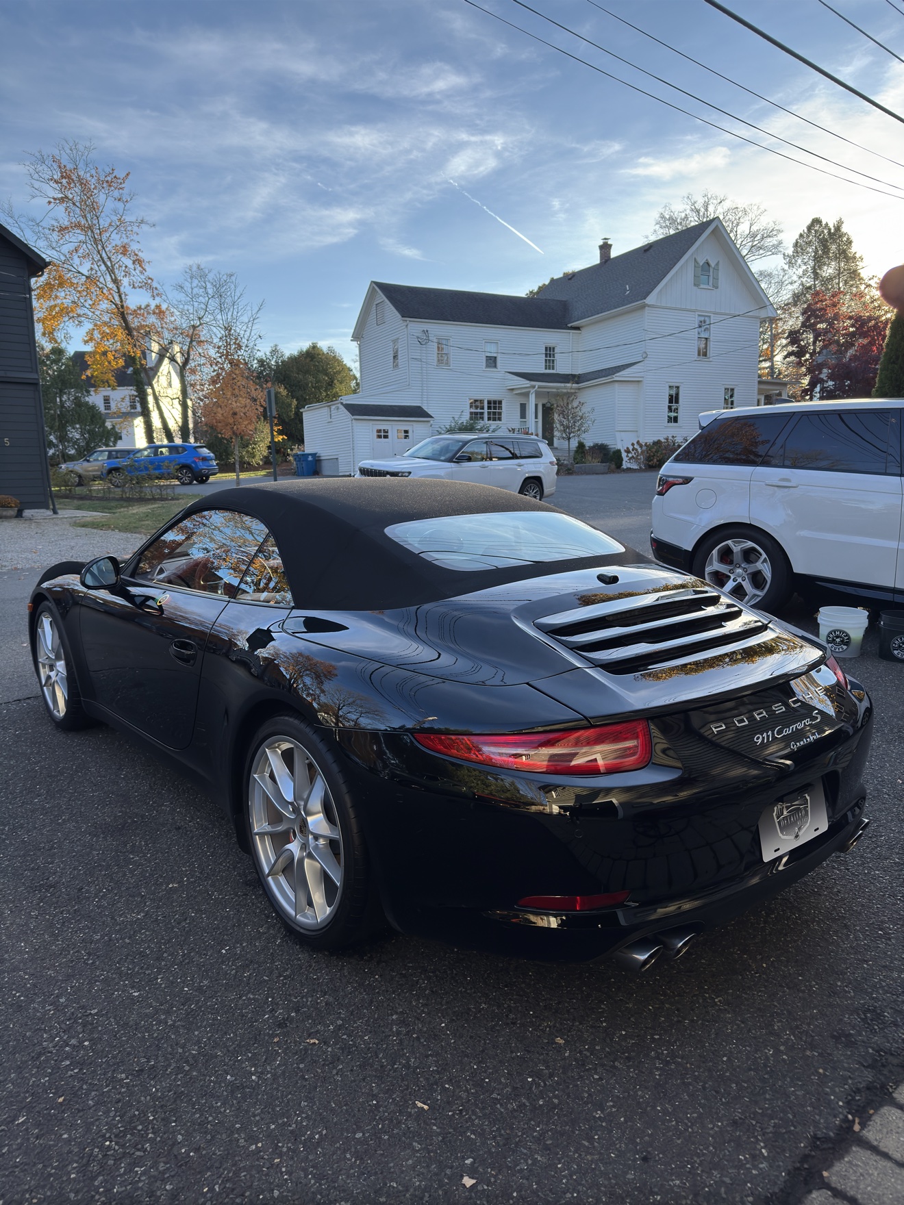 Black Porsche 911 Carrera S convertible rear three-quarter view with soft top up