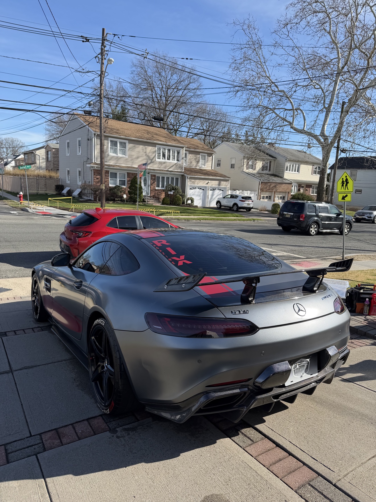 Rear three-quarter view of a matte gray Mercedes AMG GTS with rear wing and GTS badge