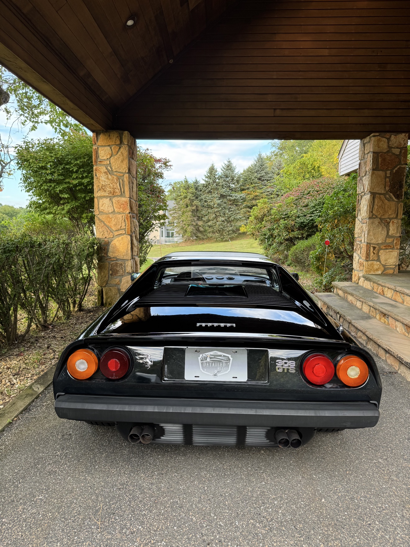 Rear view of a black Ferrari 308 GTS with 308 GTS badge and Detailed by Yael plate frame