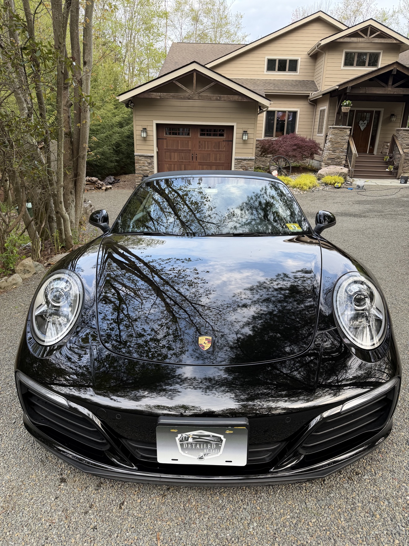 Front view of a black Porsche 911 Carrera Cabriolet with Detailed by Yael plate frame