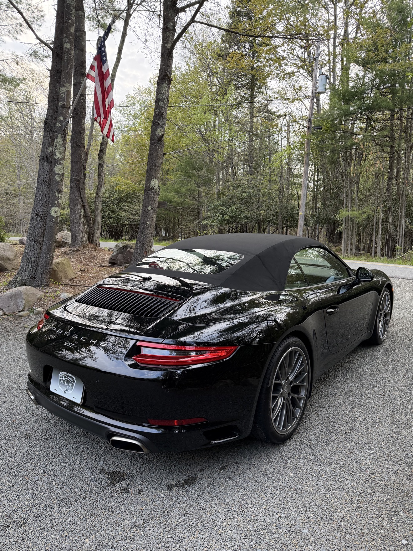 Black Porsche 911 Carrera Cabriolet rear angle view by the trees