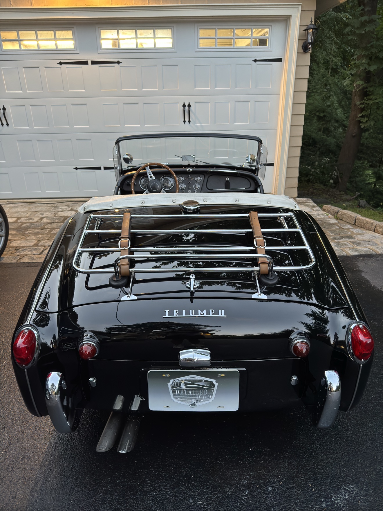 Rear view of a black Triumph TR3 with luggage rack and Detailed by Yael plate frame
