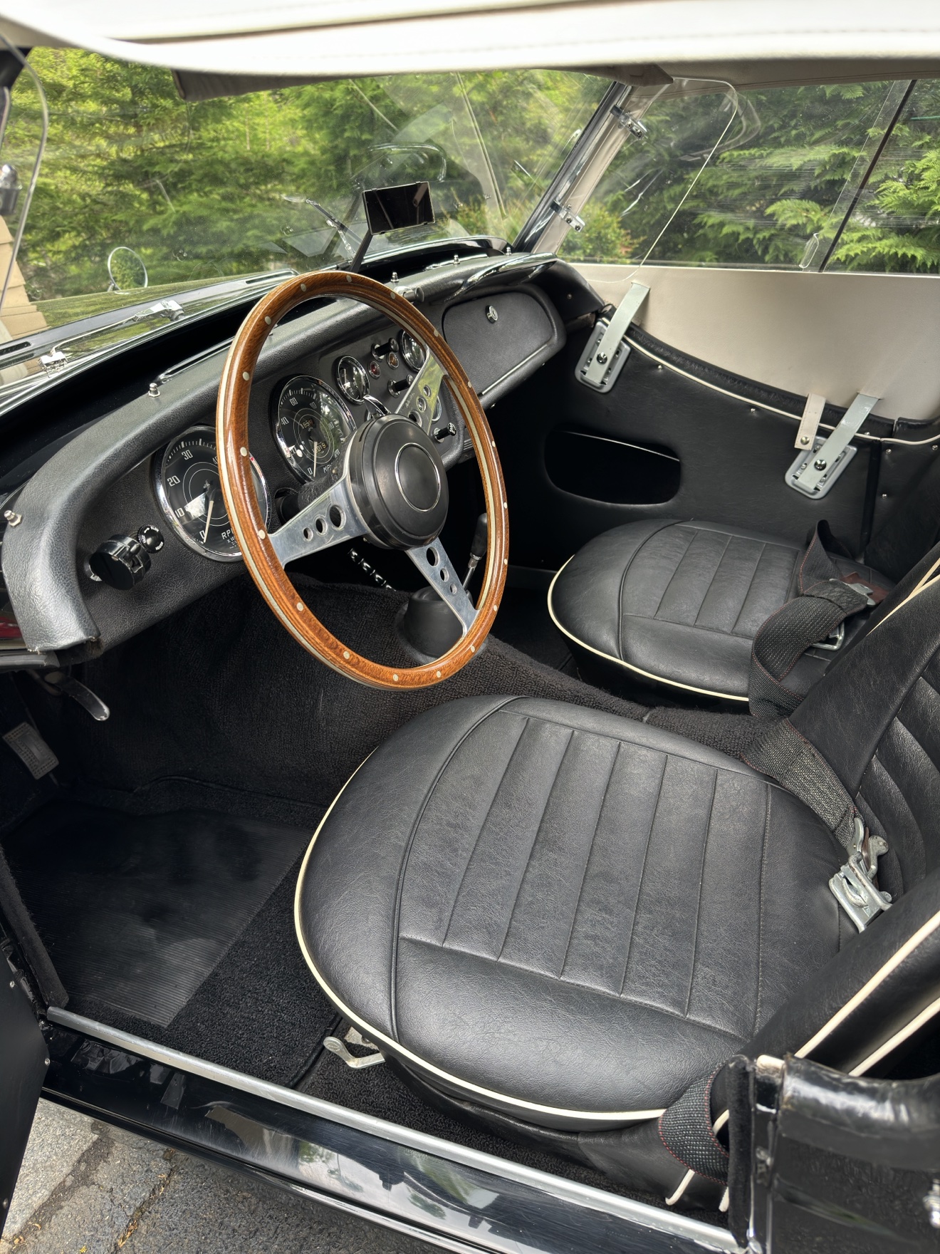 Triumph TR3 cockpit with wood steering wheel and black leather seats
