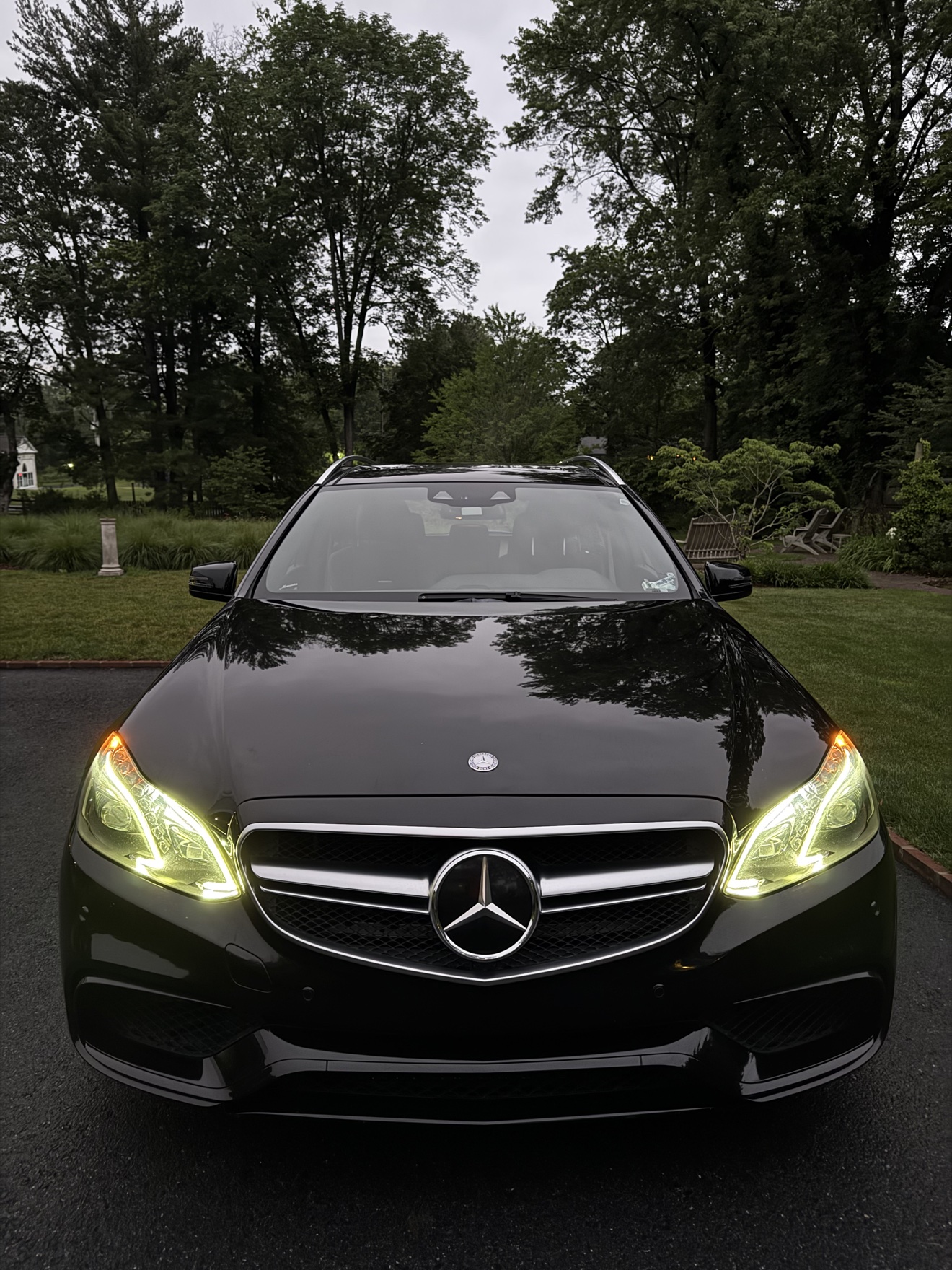 Front view of a black Mercedes Benz E63 S AMG wagon with headlights on after detailing