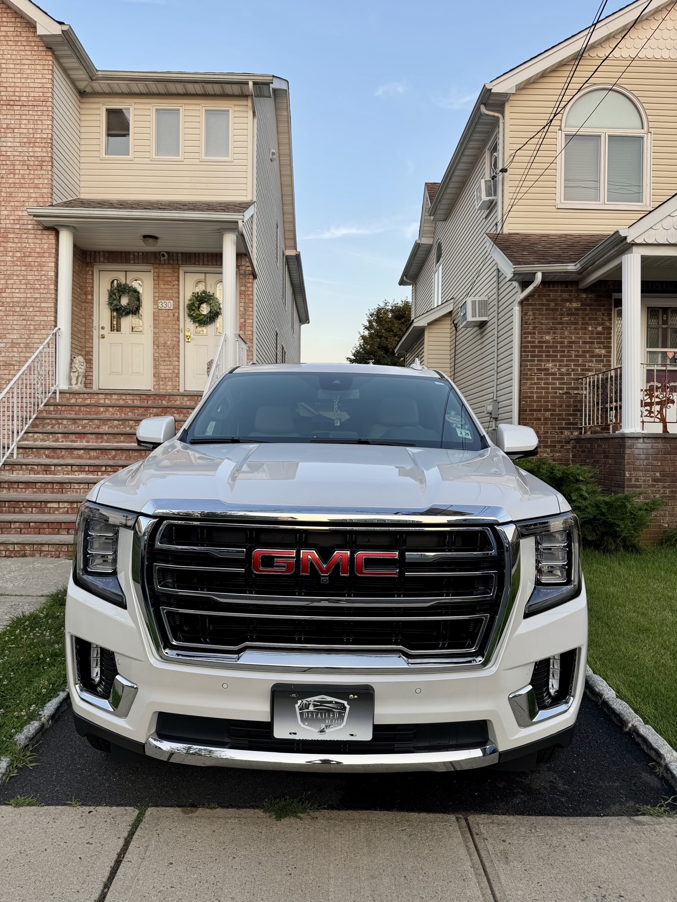 Front view of a white GMC Yukon SLT with Detailed by Yael plate frame