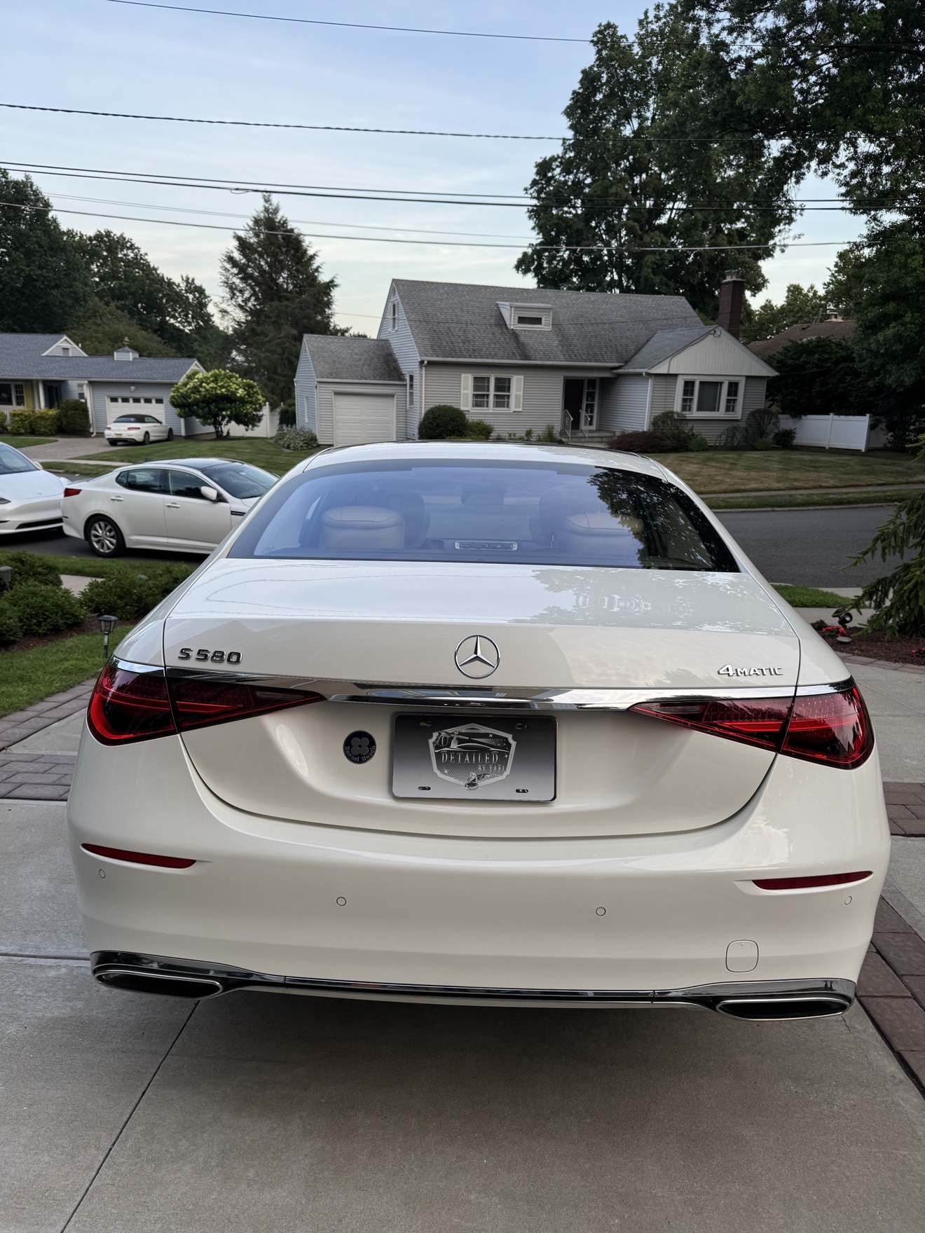 Rear view of a white Mercedes-Benz S580 with S 580 and 4MATIC badges and Detailed by Yael plate frame