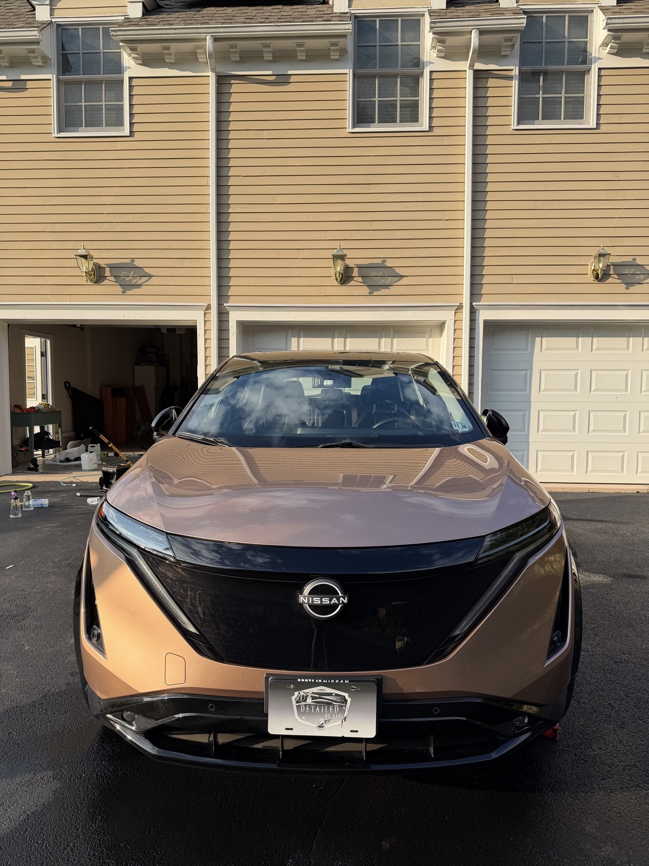 Front view of a copper Nissan Ariya with Detailed by Yael plate frame