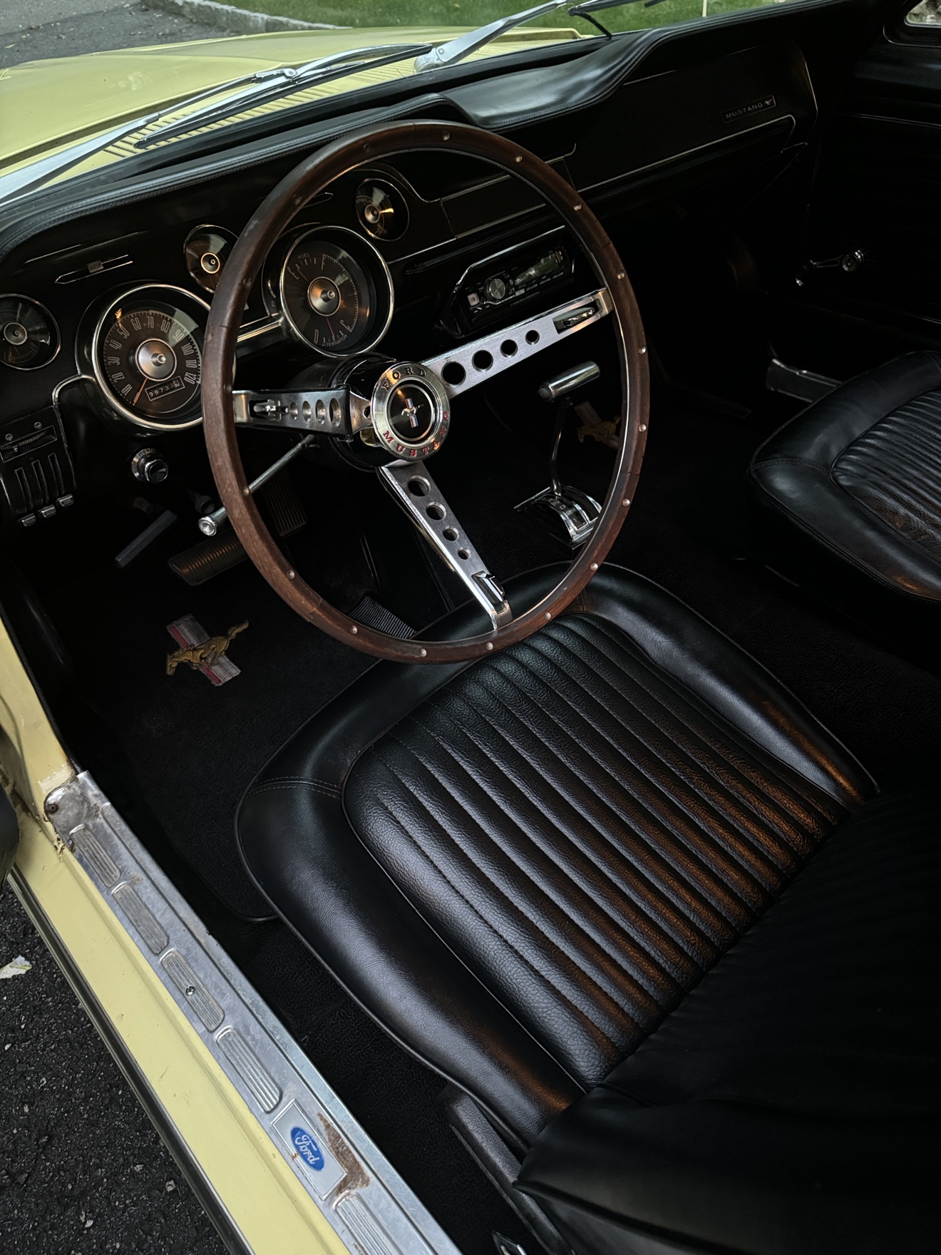 1968 Ford Mustang driver interior with wood steering wheel and black leather seats