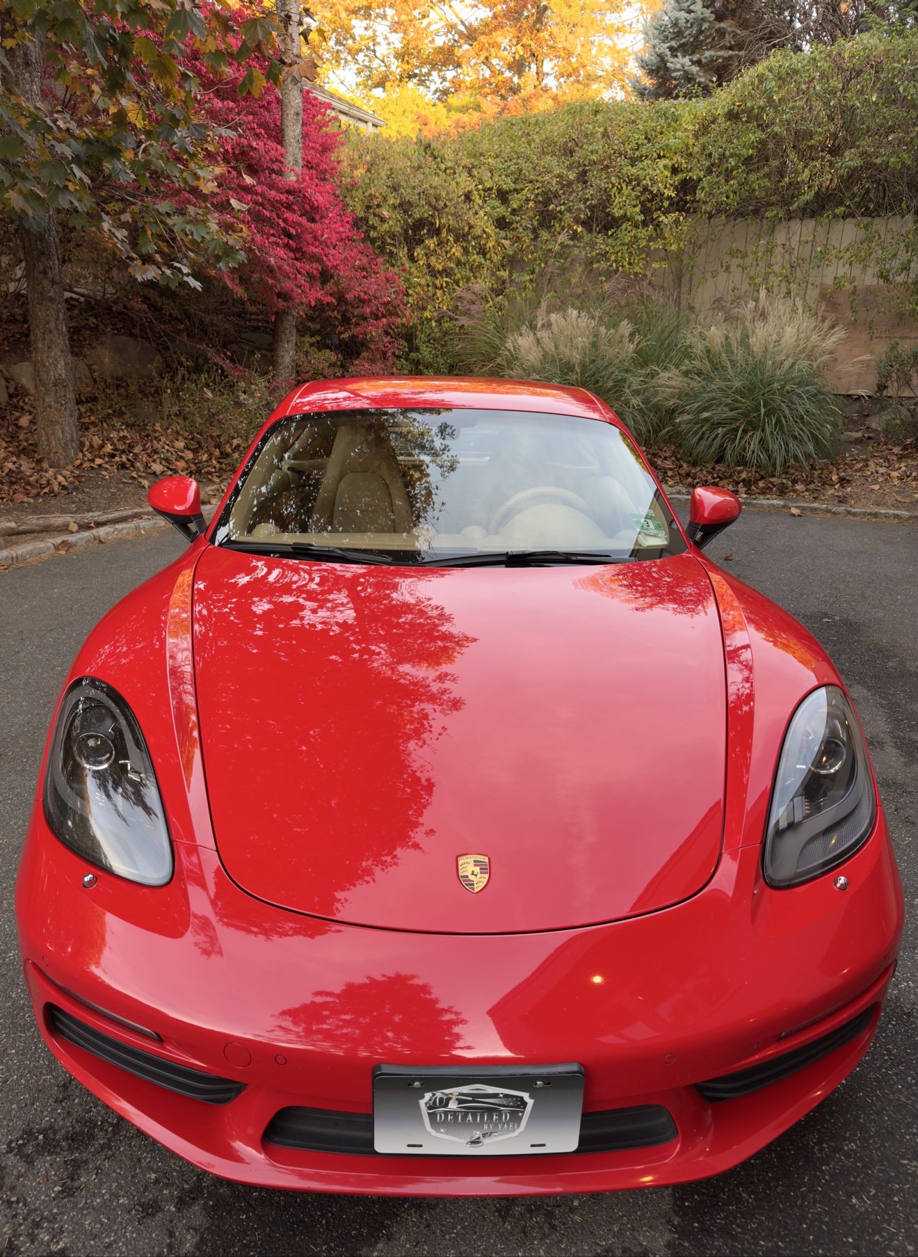 Red Porsche 718 Cayman front view with Detailed by Yael plate frame